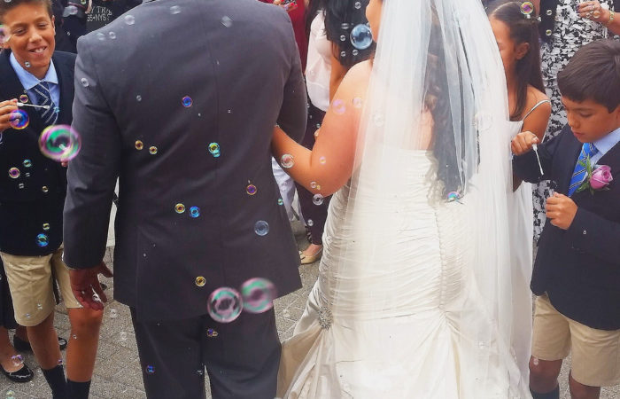 Newlyweds walking as people around them blow bubbles
